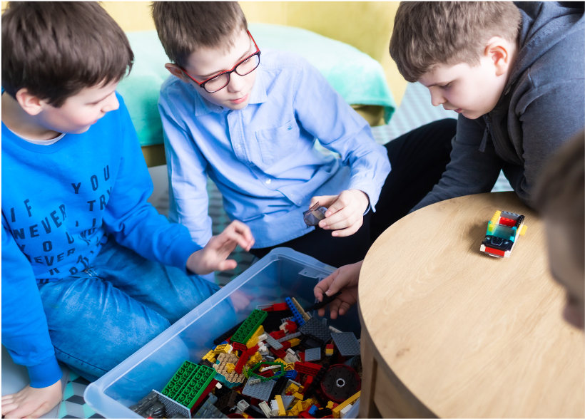 trzech chłopców budujących z klocków lego