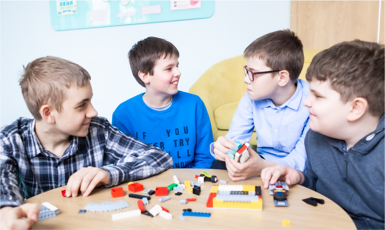 czterech chłopców układających klocki lego