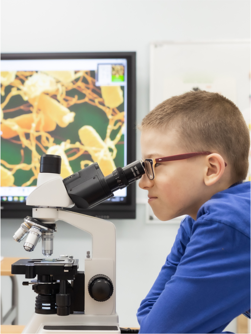 chłopiec patrzący przez mikroskop